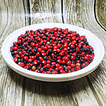 A pile of vivid red and black Abrus Precatorius seeds known as Chirmi Ratti Gunja lucky beads scattered on a white background showing their characteristic two-toned glossy surface - Variation