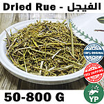 Close-up of dried Moroccan rue herb (Ruta Graveolens) with green stems and small flowers in a white ceramic bowl on a rustic wooden surface
