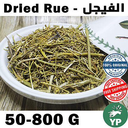Close-up of dried Moroccan rue herb (Ruta Graveolens) with green stems and small flowers in a white ceramic bowl on a rustic wooden surface