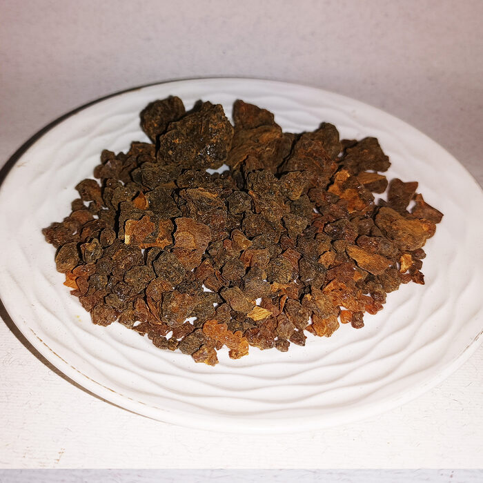 Whole dark amber-brown myrrh resin pieces (Commiphora myrrha) displayed on a white ceramic plate, showing natural texture and color variation - Variation