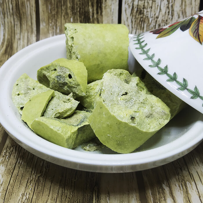 Raw yellowish-green natural sulfur mineral chunks displayed in a white decorative Moroccan dish on a wooden surface - Variation