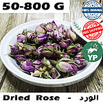 Whole dried purple-pink rose buds piled in a white ceramic bowl on a rustic wooden surface
